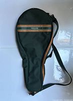 Full view of dark green oval-shaped tennis bag with brown leather trim and adjustable strap.