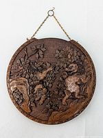 Front view of round Chinese carved cinnabar lacquer charger showing two mythical lion creatures and floral design with metal hanging chain