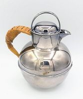 Front and side views of silver-plated teapot showing its round shape, spout, hinged lid, and wicker handle.