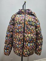 Front view of a youth large puffer jacket with a colorful print of cartoon characters and a zippered chest pocket with button detail