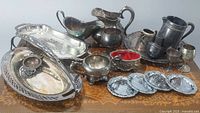 Overview of the lot showing multiple plate silver items including trays, pitchers, and bowls.