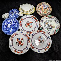 Overhead photo displaying all items: three large Old Imari style plates with floral design, three smaller floral plates, blue willow plate, oriental scenic plates, small white creamer and cup