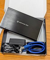 Top view of the aluminum external hard drive enclosure inside the box with power supply and blue USB cable included.