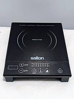 Top view of the black induction cooktop showing the cooking surface and control panel with buttons and power settings.