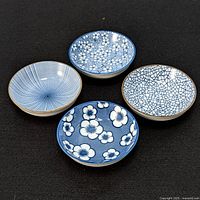 Four small porcelain bowls shown on black background, displaying top inside of each bowl with different intricate blue patterns on white porcelain.