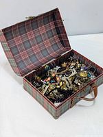 Open plaid box showing assorted tangled costume jewelry inside