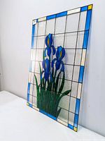 Angled side view of stained glass style window panel showing the blue and yellow iris flower design and grid pattern background.