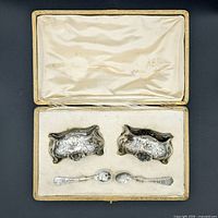 Full view of the antique salt cellar set showing two salt cellars and two spoons in their original fitted presentation case with silk lining.
