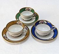 Photo showing the three cups and saucers with green, yellow, and blue color accent bands, hand-applied 24ct gold gilding, and floral details.