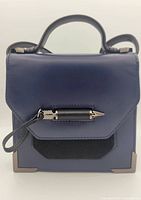 Front view of navy blue women's crossbody purse showing flap closure with silver decorative hardware and wristlet strap.