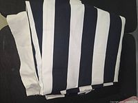 Folded black and white wide striped fabric displayed spread out to show pattern and texture.