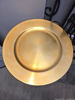 Single gold charger plate with metallic finish and smooth edge.