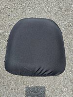Black cushion seat cover displayed on pavement to show fabric and elastic edges.