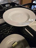 White ceramic salad bowl with wide rim in a black crate showing the shape and finish clearly.