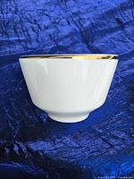 Side view of a white ceramic soup cup showing the gold rim detail.