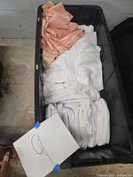 Top-down view of black bin filled with folded white and peach round table linens