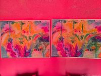 Close-up of two colorful abstract paintings side by side on a pink wall.