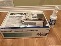 Photo of the Kenmore air cleaner box with the unit and the Dax air cleaner detergent spray bottle placed on top, showing brand and product title.