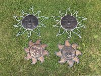 Four decorative sun faces on grass, two larger wire ray designs on top and two smaller solid ray designs below