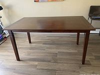 Front view showing rectangular shape and tapered legs on tiled floor.