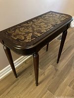 Full view of the wooden foyer table showing the tapered legs, rounded corners, and floral inlay on the top with dark wood finish.