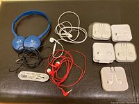 Full lot visible with all 9 headphones and earbuds arranged on a dark surface to show condition and variety.