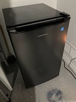 Front angle view of the black Hamilton Beach mini fridge showing brand name and overall condition.