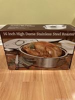 Photo of front of box showing 16 inch high dome stainless steel roaster with image of roasted turkey inside the roaster.
