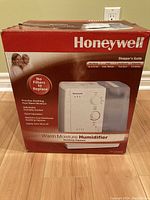 Photo of the Amber and red box packaging for Honeywell Warm Moisture Humidifier with product image and features