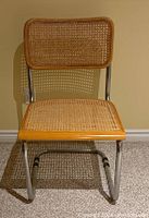 Front view of cane back and seat chair with wood trim and chrome legs