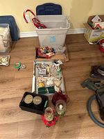 Wide shot of Christmas decorations including plaque, ornaments, candles, lanterns, and storage bin on floor