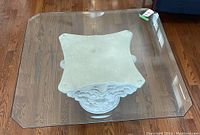 Top view showing clear square beveled glass surface resting on decorative white carved base