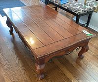Angled front view of rectangular wood coffee table on wood floor, showing top and legs.