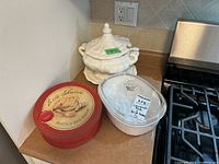 Corning Ware French White casserole, Eatons ceramic tureen set and ceramic Brie baker on kitchen counter.