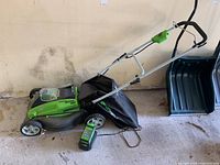 Right side view of Greenworks electric lawn mower with charger connected and grass bag attached