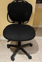Front view of black IKEA office chair with mesh backrest and cushioned fabric seat on wheelbase.