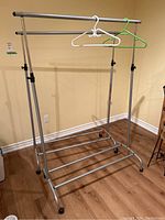 Front view of one adjustable metal rolling clothes rack with hangers.