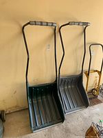 Front view of two Yardworks sleigh snow shovels, one green and one gray with foam handles.