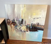 Abstract textured print on large square canvas leaning against wall on floor.