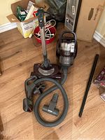 Full overview of vacuum components including main unit, hose, wand, and attachments laid out on wood floor.