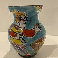 Front view of the large hand-painted Italian pottery vase showing a figure holding fruit with a blue background and a flared rim.