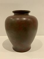 Front view of the large bronze Japanese vase showing its rounded smooth shape and natural aged patina blending reddish with greenish hues.