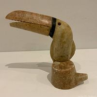 Side view of the hand-carved bird sculpture showing the profile and the beak with repair.