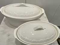 Set of three white vintage oval terrines with original lids, showing the front and top views and the scalloped edge details.