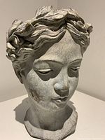 Frontal close-up showing detailed facial features and weathered cement material with minor discoloration.