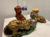 Photo of all four vintage candles showing two tigers, orange foo dog, and yellow-orange cylindrical candle with size reference by water bottle