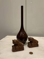Front view of vintage brown Japanese vase with two hand-carved stone lions next to it on a white surface