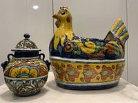 Colorful vintage Mexican pottery chicken planter and lidded jar on a shelf, showing detailed floral and leaf patterns with bright yellow and blue tones.
