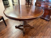 Full view of the round pedestal table showing the smooth, polished mahogany wood top and pedestal base.