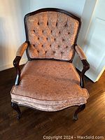 Front view of the antique armchair showing button tufted upholstery and mahogany wood frame.
